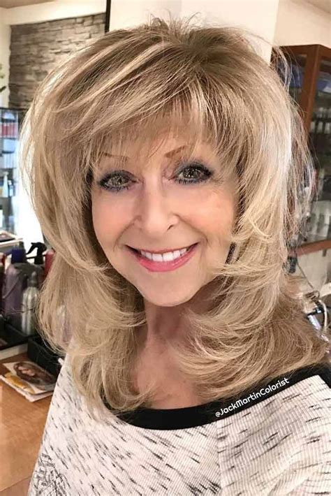 Mid length haircuts for women over 50 - 28. Feathery Layers and Bangs Combo. For women over 50 with long layered hair, bangs can be a great option to add a modern and youthful touch to the look. Layered cuts with bangs give the locks more life and is great for those who want a change while keeping the length. @danieloliveirahairstylist.